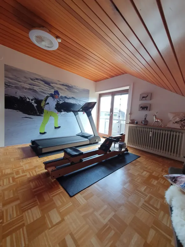 Laufband und Rudergerät im Privat-Studio, dahinter ein großes Sport-Wandbild