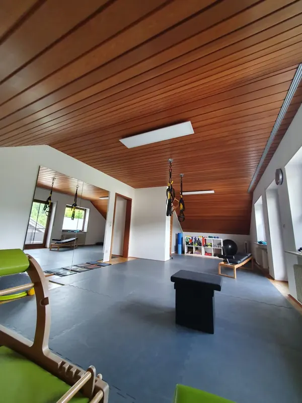Trainingsbereich mit Übungsbank und Geräten unter der Holzdecke des Studios