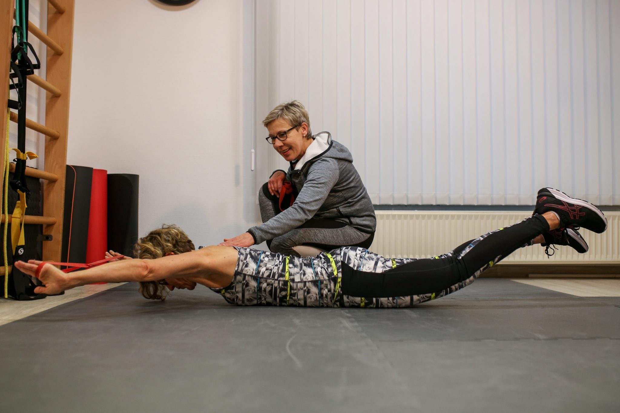 Personal Trainerin Suse zeigt einer Kundin in Bammental eine Mobilisationsübung gegen Schmerzen durch Bewegungsmangel.